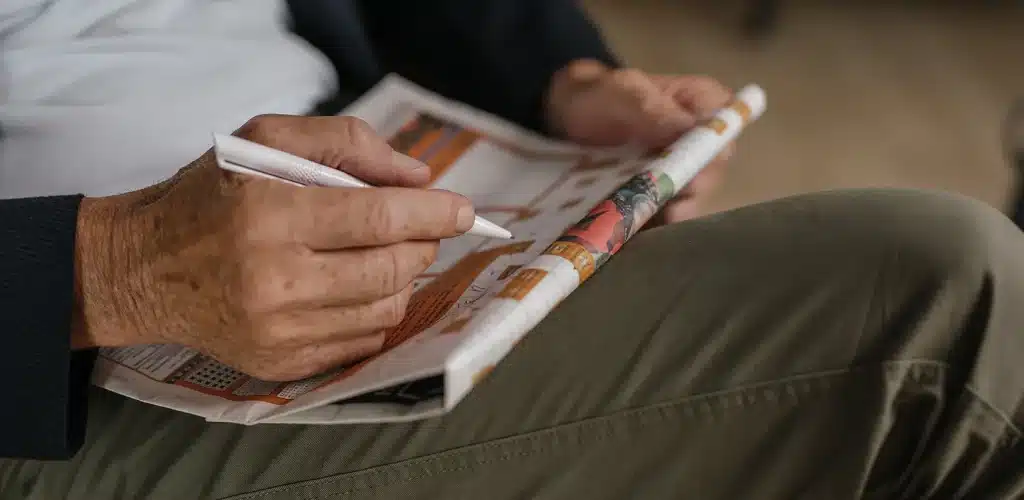 Close-up of a person solving a puzzle in a Keesing puzzle magazine with a pen.
