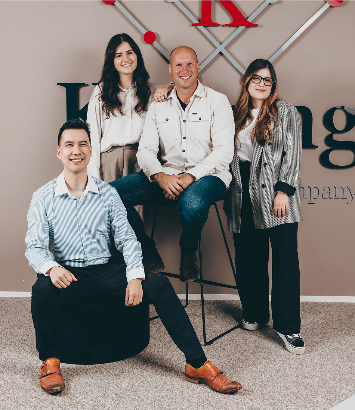 Four colleagues posing and smiling together in a professional group photo.